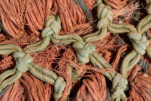 A green and yellow knot linked rope interlaced with strands of orange rope.