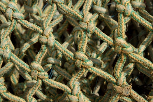 A linked, lined, knotted pattern made from green and yellow rope with depth.