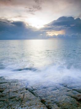 Landscape of sea with wave and rock in sunset.