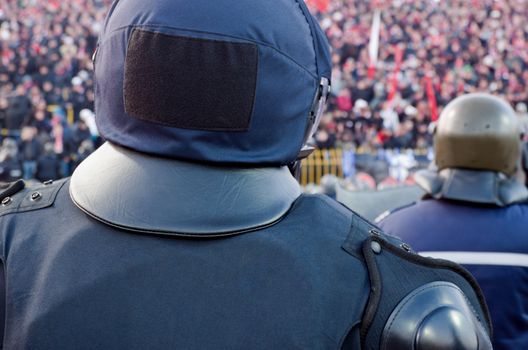 Shot of the back of policeman with helmet guarding a sport event
