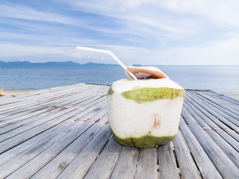 Coconut Water Drink on bamboo table with sea background