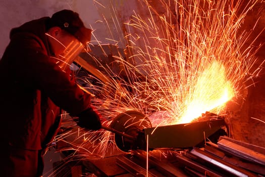 worker white hot sparks at grinding steel material