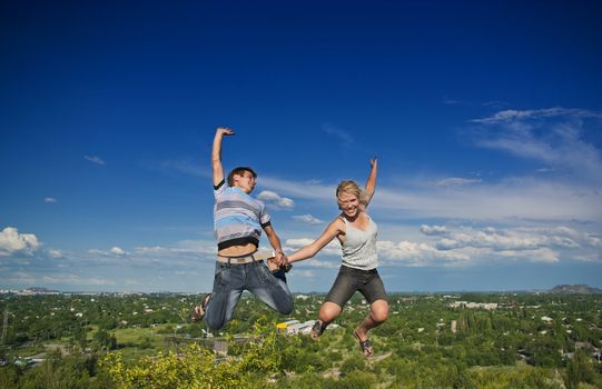 Boy and girl jumping against a background of beautiful sky