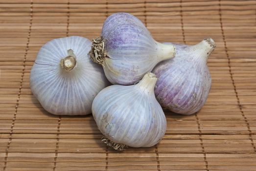 Four garlic on wood background