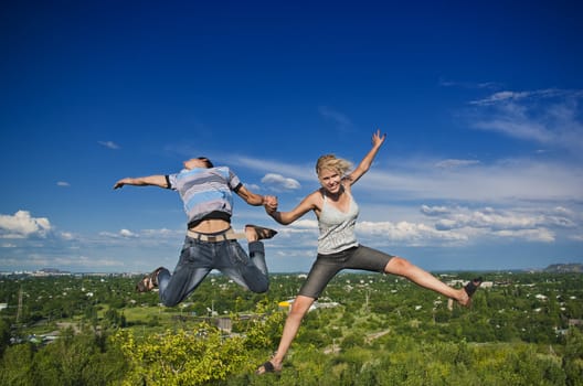 Boy and girl jumping against a background of beautiful sky