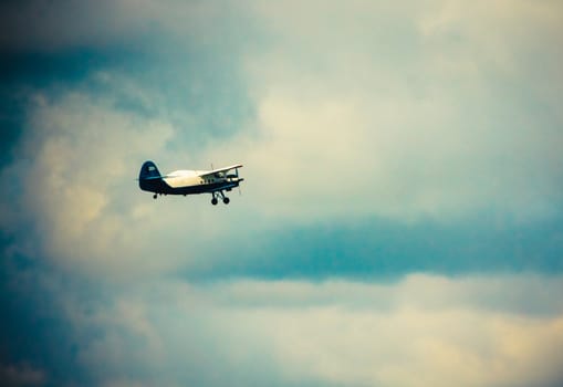 Biplane In Blue Sky Over Clouds