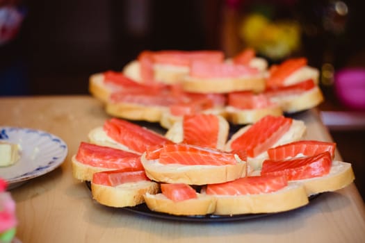 Sandwiches with smoked salmon and arugula on a black plate and wooden board