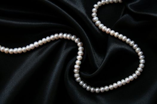 White pearls on the black velvet background 