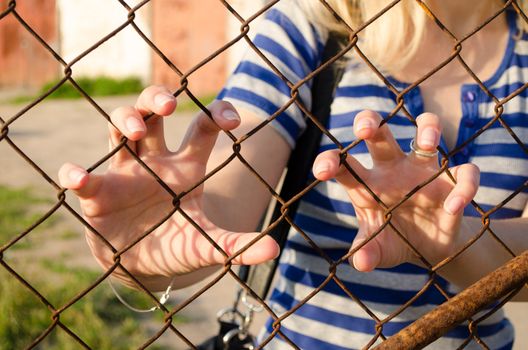 Woman claw hands rusty fence. Human movement freedom restrictions.