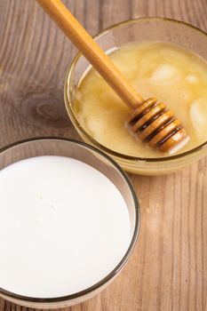 Milk and honey on the wooden table closeup