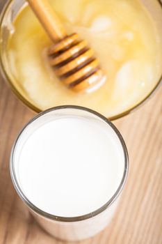 Milk and honey on the wooden table closeup