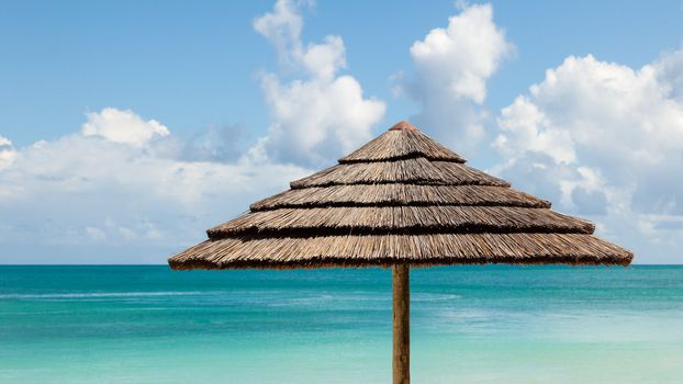 Beautiful Sunny Tropical Seascape of Beach Umbrella by Sea and Sky with Fluffy Clouds and Copy Space