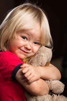 A cute injured little boy hugs his stuffed toy puppy dog