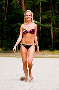 A young and beautiful woman walking along the sandy beach