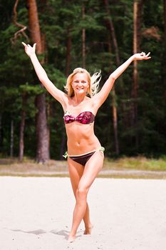 A young and beautiful woman walking along the sandy beach