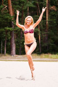 A young and beautiful woman walking along the sandy beach