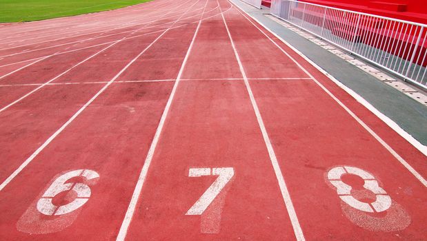 Lanes of a red race track with numbers and red seats in the stadium     