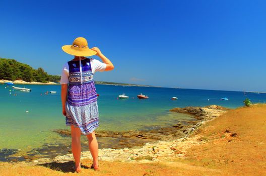 Woman is observing small port and boats on summer day.