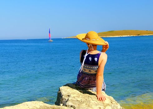 Young woman observing small sailing ship.