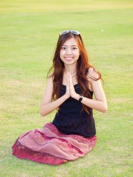 a portrait of attractive asian woman greeting on green grass field