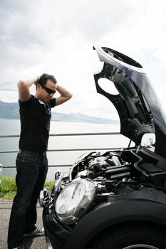 sad man looking at his broken car