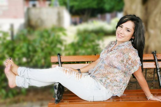 Portrait of smiling young girl sitting in bank in park