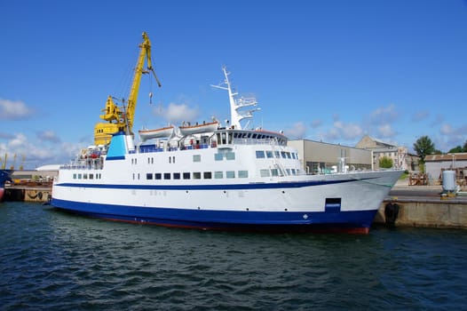 Small white passenger ferry costs in port