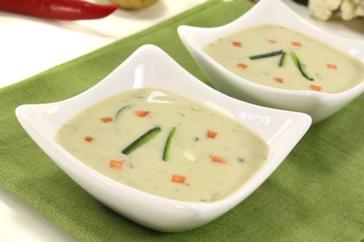 delicious fresh vegetable creme soup with zucchini and carrots on a light background