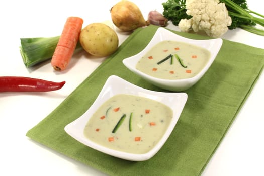 fresh vegetable creme soup with zucchini and carrots on a green napkin before light background