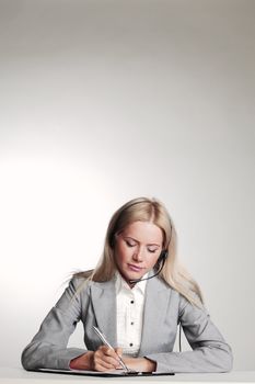 business woman in a headset writing in notebook