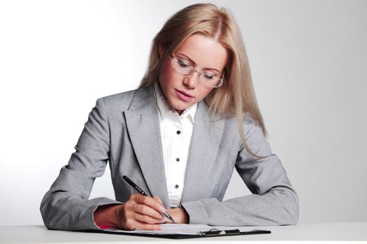 business woman writing in notebook on a gray background