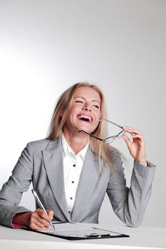 business woman writing in notebook on a gray background