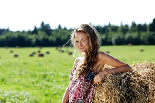portrait of a girl next to a stack of hay under the blue sky