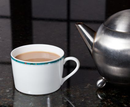 Fresh tea poured into white cup on marble kitchen worktop