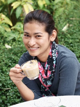 Asian woman holding a cup of tea or coffee and smiling