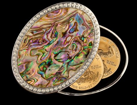 Isolated oval mother of pearl jewelry box with pure gold coins as savings