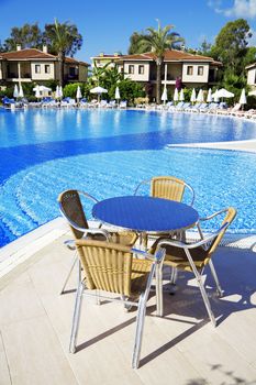 table and chairs near a cool pool in a hot canicular day