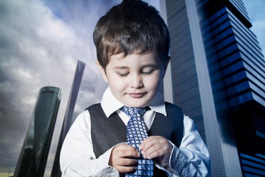 child dressed businessman with hands in his tie and skyscrapers in the background