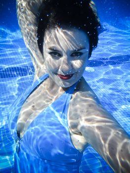 Vintage girl swimming and smiling underwater in a swimming pool