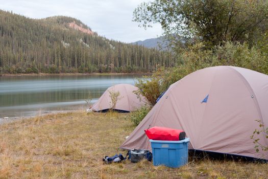 Camp of two tents pitched up on shore of Yukon River in remote wilderness of Yukon Territory, Canada