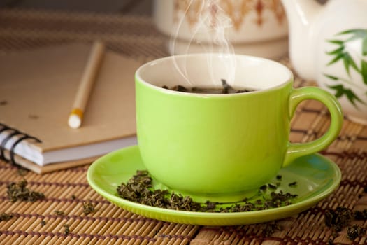 green cup of hot tea on wood background