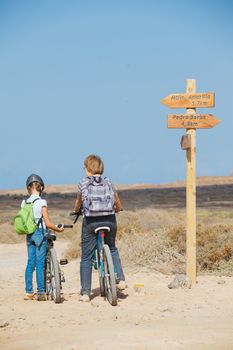 Back view of girl with her grandmother having a weekend excursion on their bikes on a summer day in beautiful landscape