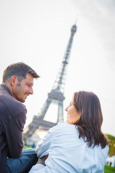 Young romantic couple sitting near the Eiffel Tower in Paris