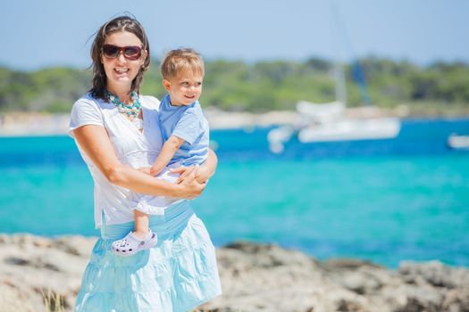 Young beautiful woman wis her son walking along tropical beach