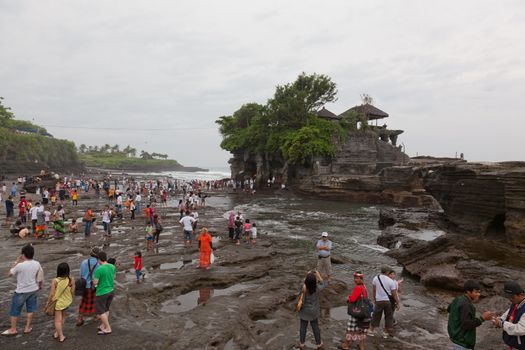 Tourists on an ocean coast near the temple Tana Lot, Bali, Indonesia 11.03.2012. Tanah Lot is one of the most important sea temples of Bali