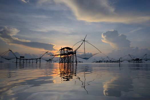 silhouette traditional fishing method using a bamboo square dip net with sunrise background in Patthalung, Thailand