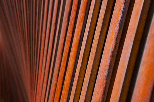 Row or pile of rusty steel rods that look lthey are desending to a dark