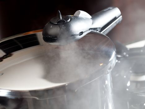 Steam escaping from lid of pressure cooker with reflection of modern kitchen