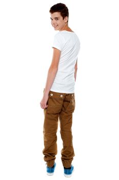 Trendy young boy turning back and smiling at camera