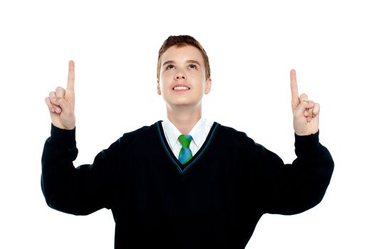 Smiling school kid indicating upwards wearing uniform